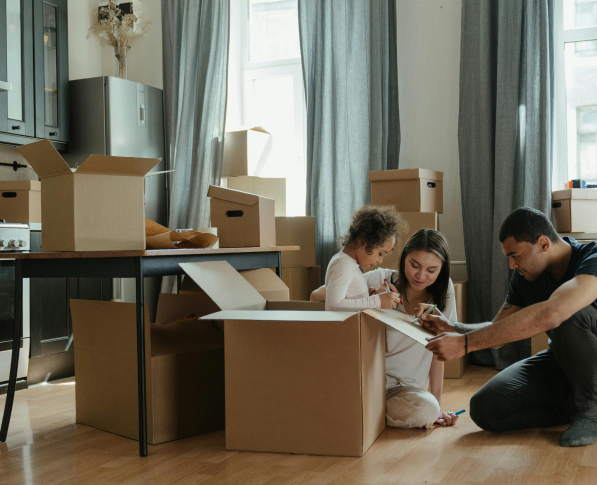 Family sitting on the floor next to moving boxes.